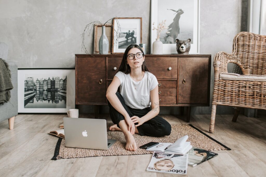 pensive young lady sitting on rug in modern apartment