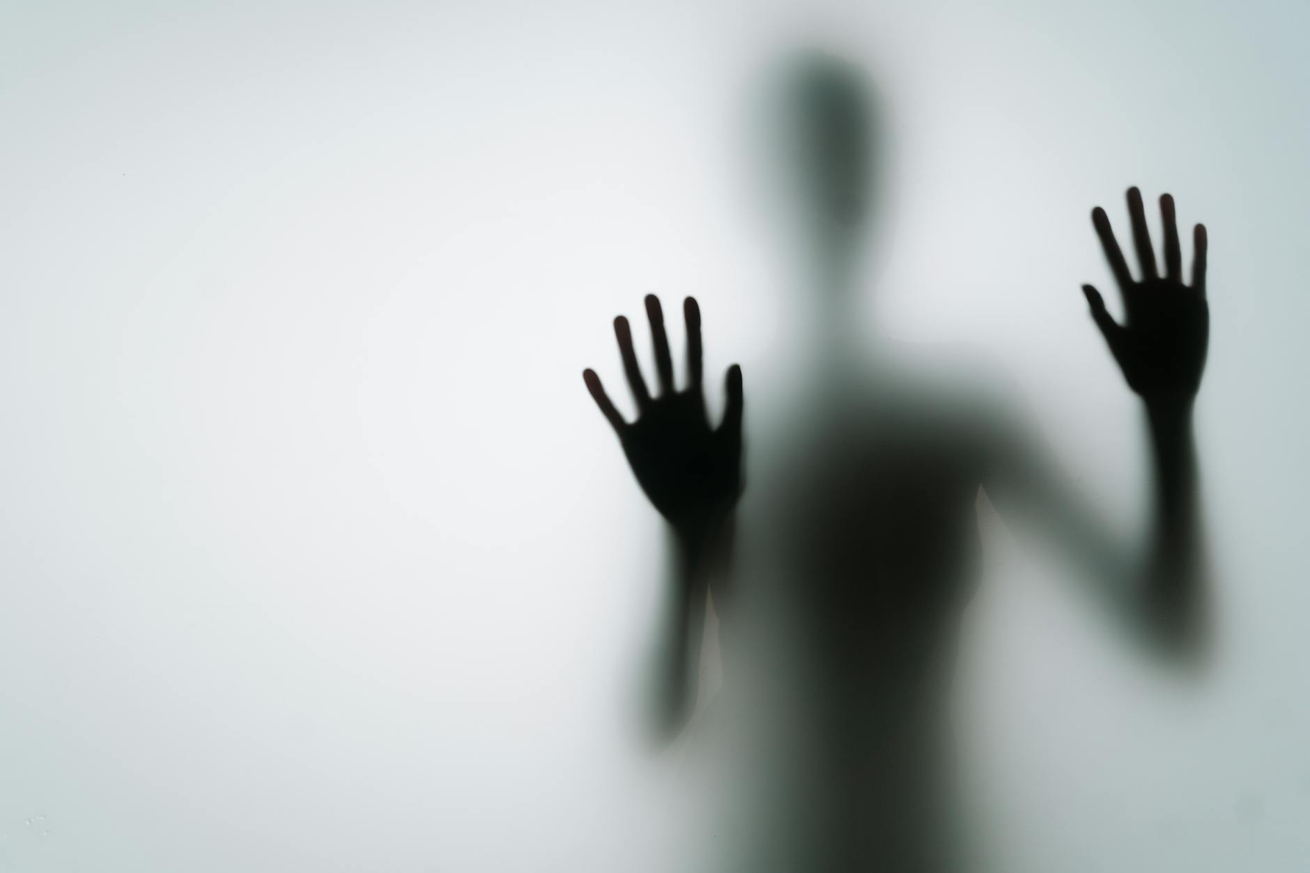 silhouette of person with hands on glass
