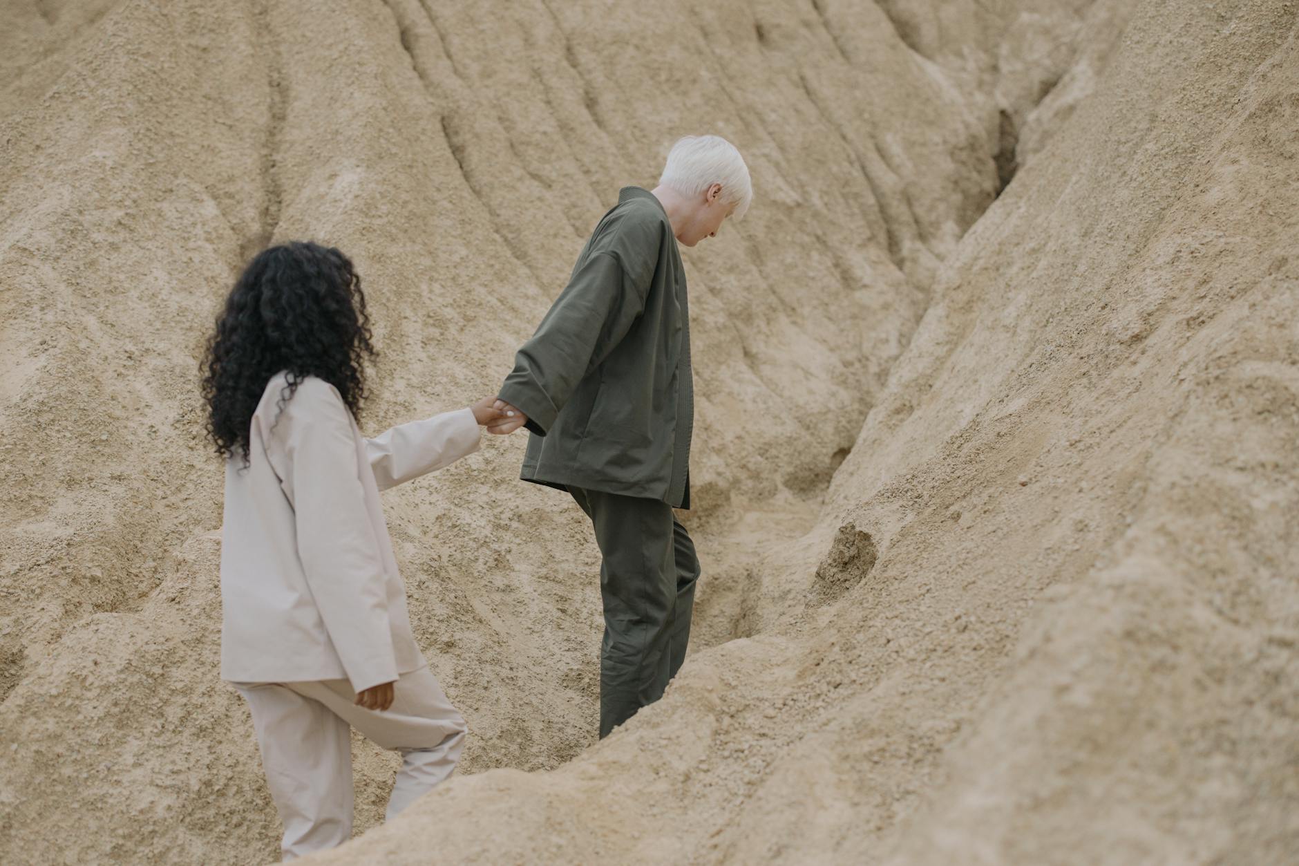 couple holding hands while walking on sand